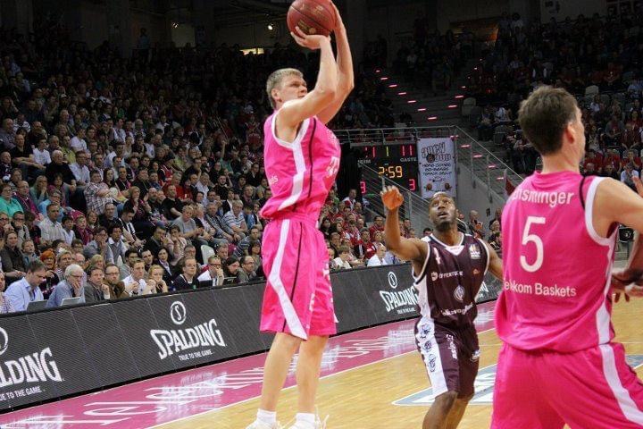 Benas Veikalas - professional basketball player Mortgage Broker Slam Dunk Mortgage Team Viera Melbourne Florida, in pink uniform shooting a ball during a game. Other players and spectators are visible in the background.