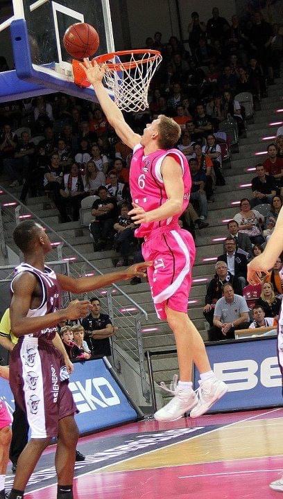 Benas Veikalas - professional basketball player Mortgage Broker Slam Dunk Mortgage Team Viera Melbourne Florida, in pink jersey basketball player mid-air in game.