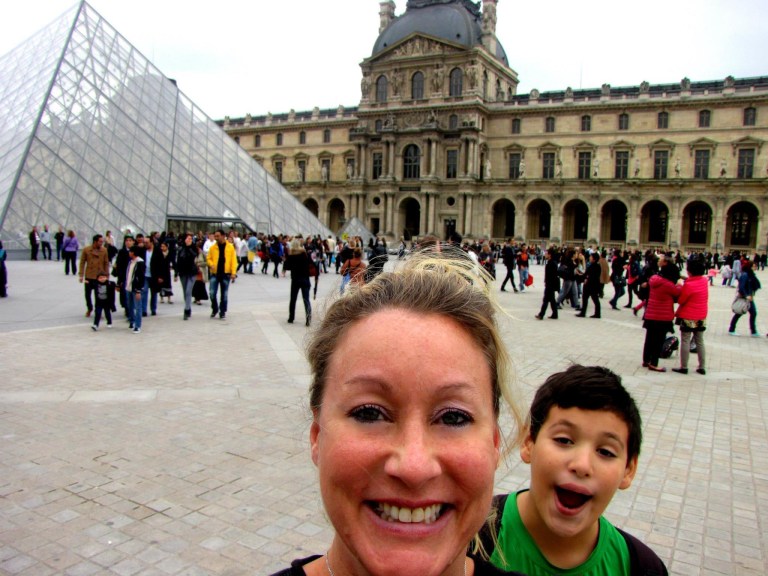 Stacey Sandlin Benas Veikalas Mortgage Broker Slam Dunk Mortgage Team Viera Melbourne Florida, family travels, in front of the iconic Louvre Pyramid and the historic Louvre Palace in Paris. It captures a moment of tourism and cultural exploration.